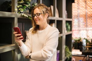 App marketing by engaging with followers. Woman looking a phone.